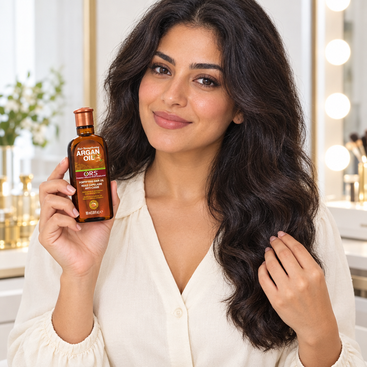 Egyptian-style model holding ORS Argan Oil beside her hair