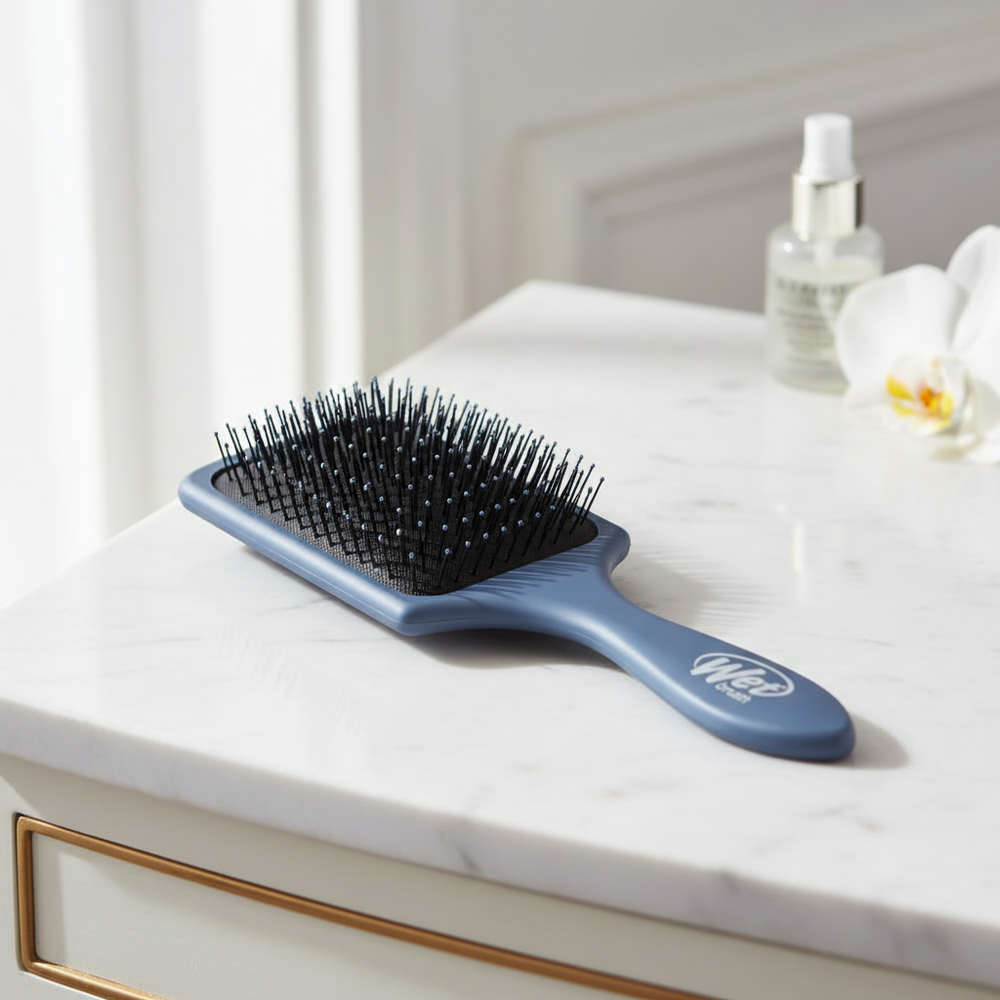 Blue-gray rectangular paddle hair brush in an elegant indoor setting