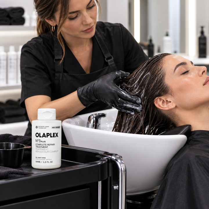 Professional hairstylist applying treatment at salon basin