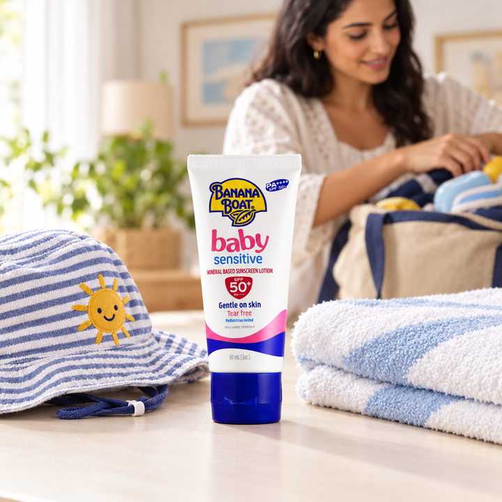 Banana Boat Baby Sensitive sunscreen beside child's sun hat and towel